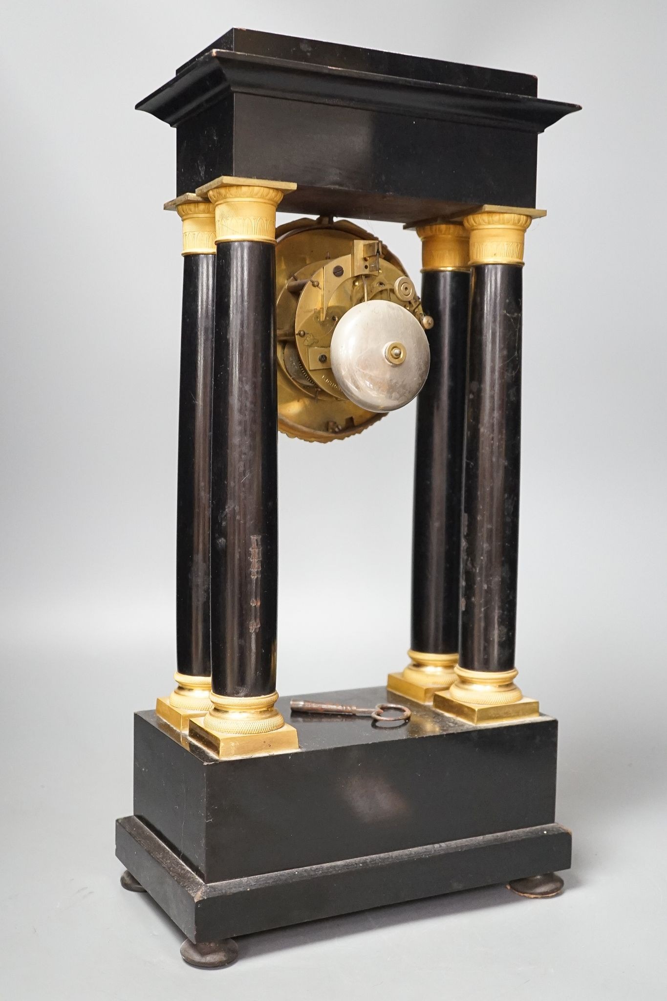 A 19th century ebonised portico mantel clock with brass mounts, 46cms high.